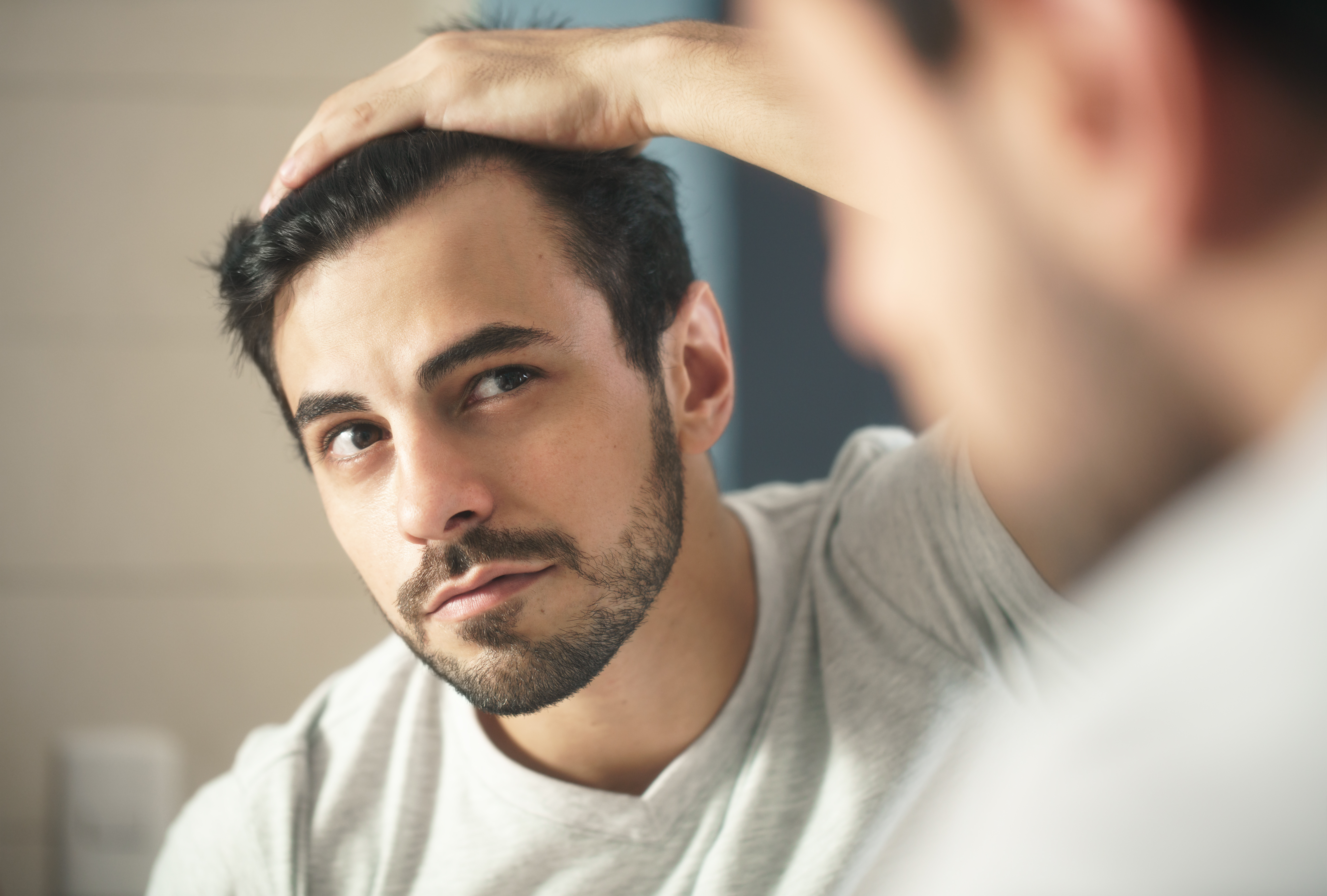 Man examining hair loss in mirror